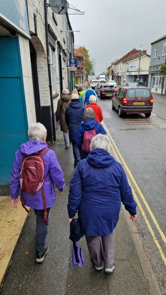 Clay Cross health walking group walking on the pavement on a rainy day.