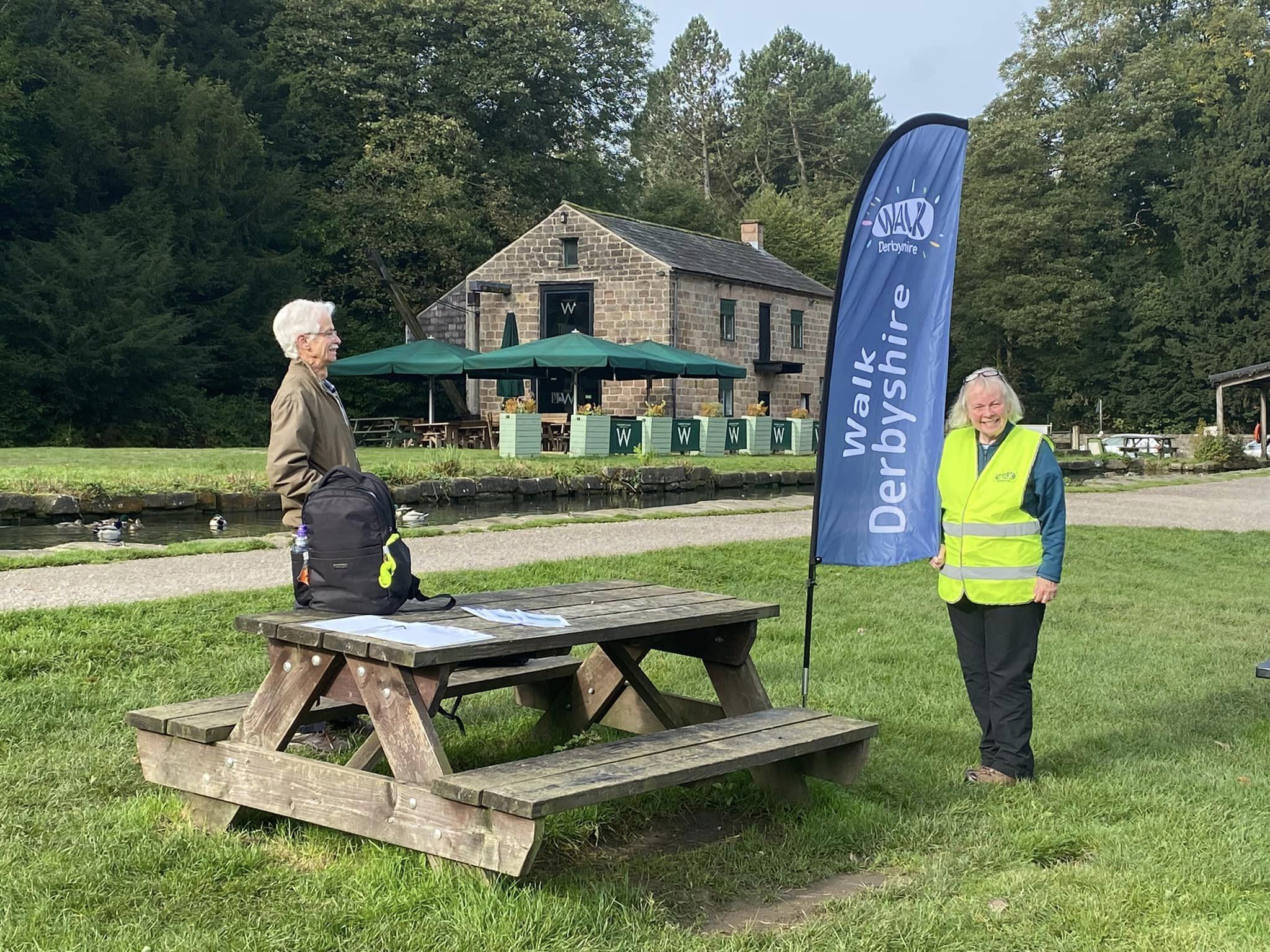 Walk Derbyshire Walk Leader in Derbyshire Dales next to Walk Derbyshire pop up flag.